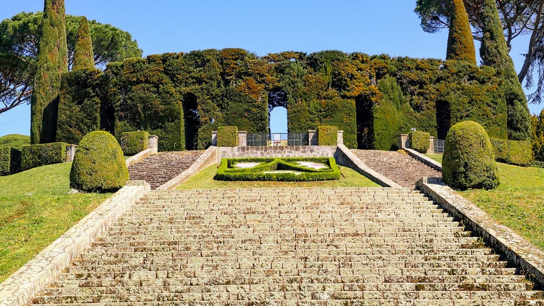 Stone steps leading to Castel Gandolfo's Secret Garden entrance, surrounded by manicured hedges.