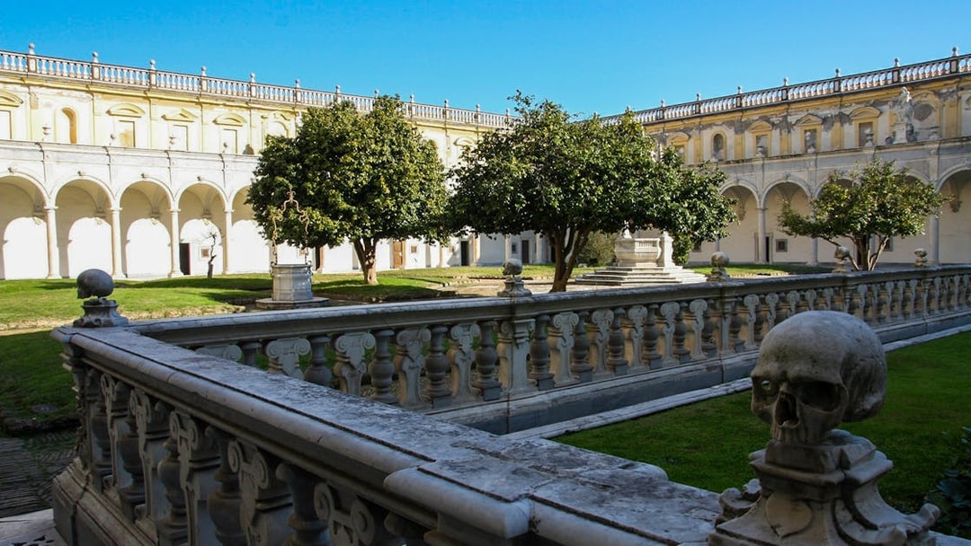 Courtyard of Certosa di San Martino in Naples with stone balustrade and trees.
