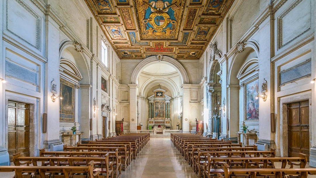Indoor view of the Basilica of San Sebastian, featuring ornate ceiling and rows of wooden pews.