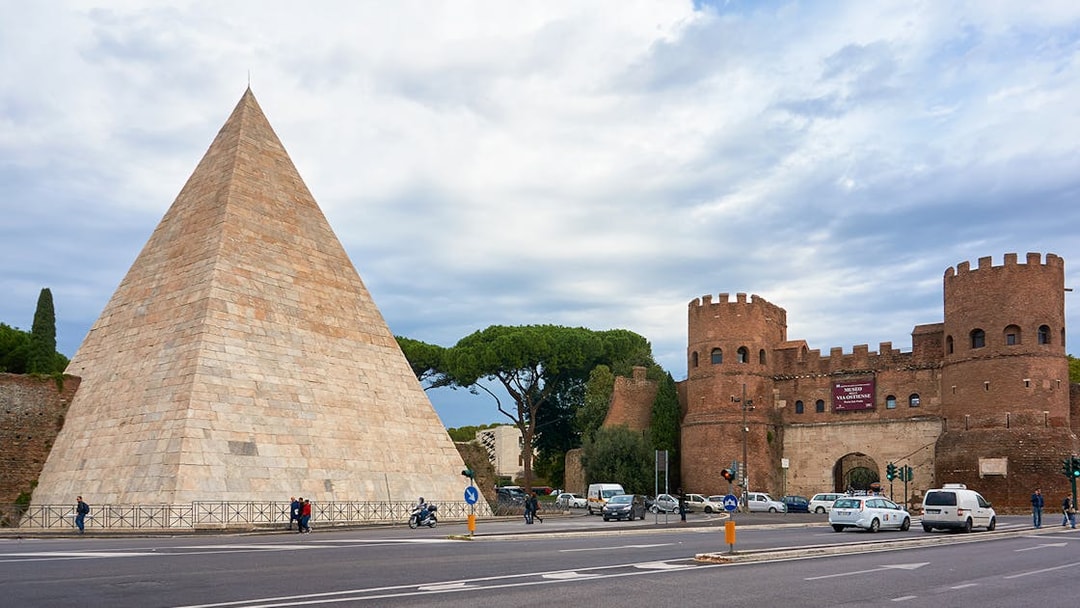 Pyramid of Caius Cestius and San Paolo Gate in Rome with passing cars.