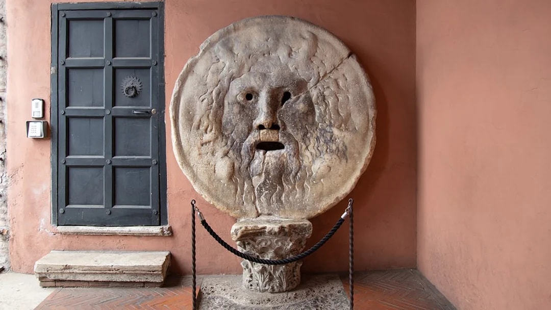 Mouth of Truth sculpture in Rome, Italy, next to a black door.