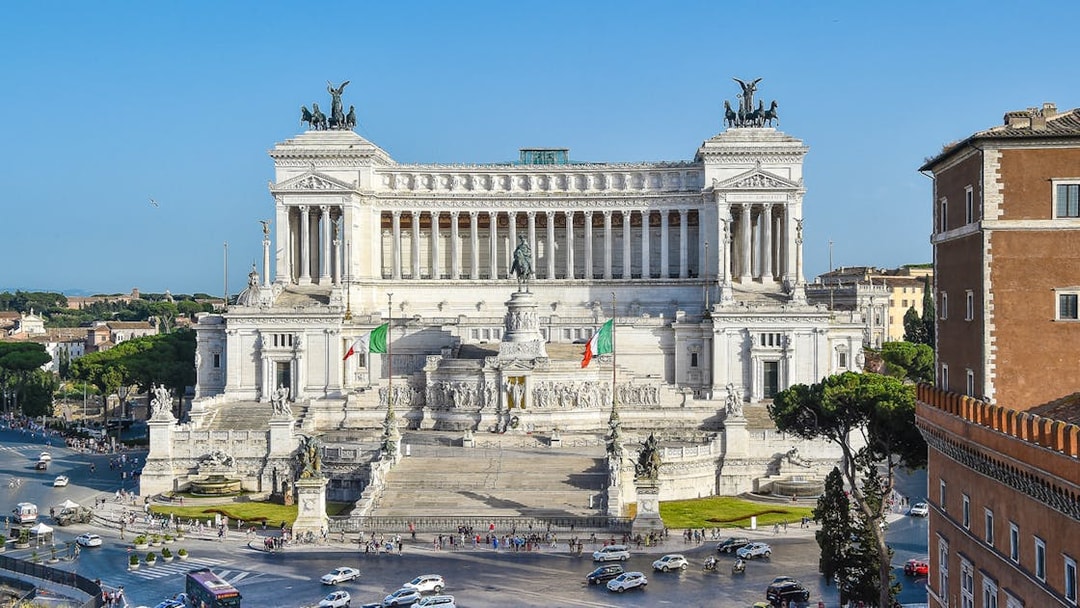 Altar of the Fatherland in Rome with Italian flags and surrounding cityscape.