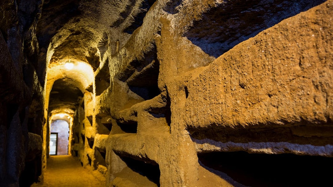 Underground passageway in the Catacombs of Saint Callixtus, Rome, with illuminated niches.