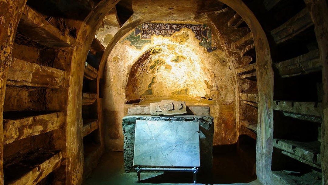 Exploring the Catacombs of San Gaudioso in Naples with ancient tombs and inscriptions.
