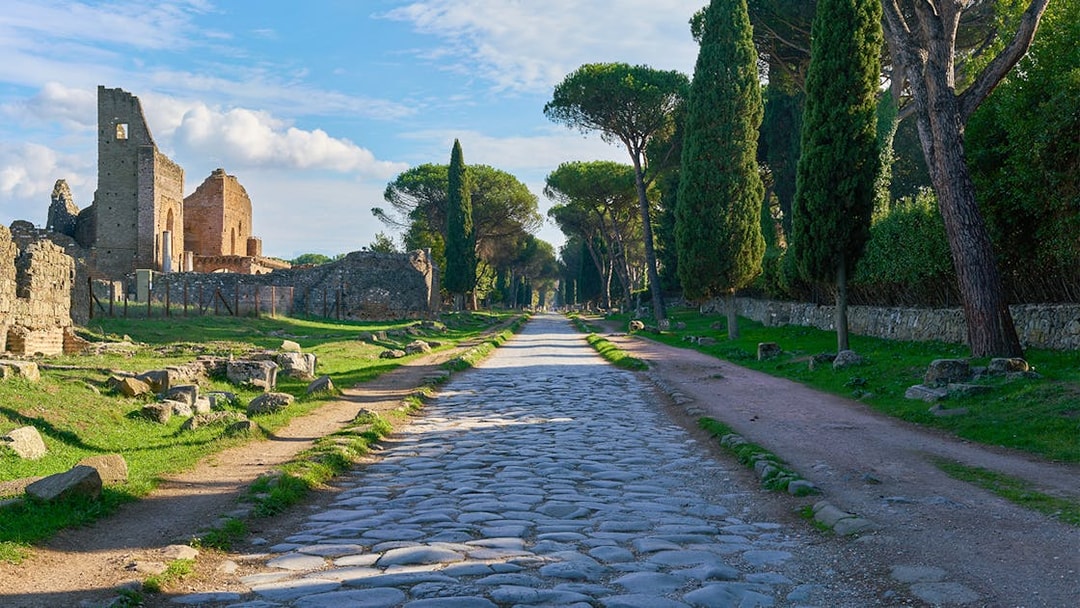 Ancient Roman road leading to the Catacombs of St. Callixtus, lined with cypress trees.