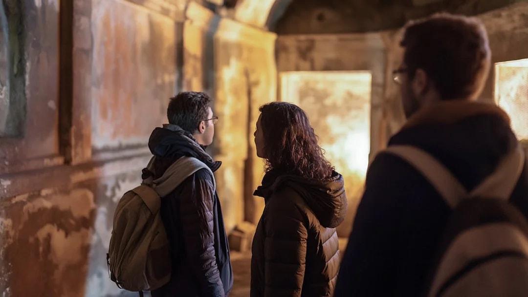 Visitors exploring underground Roman catacombs on a guided tour.