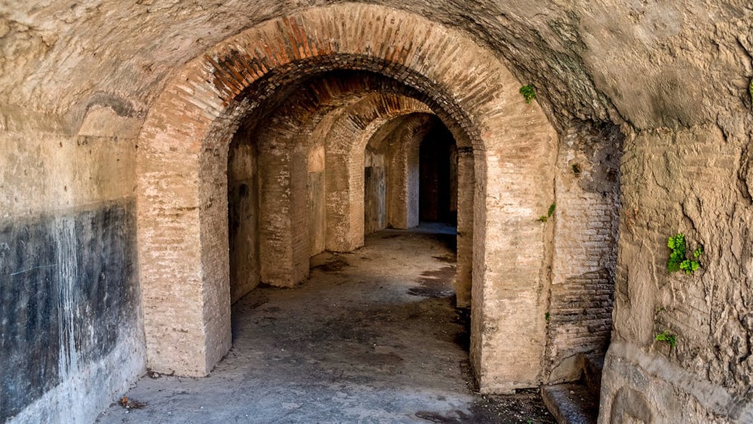 Ancient stone corridor in the Rome Catacombs with arched ceilings and walls.