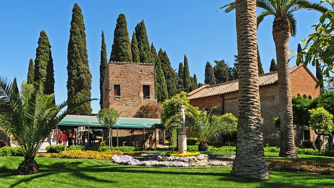 Underground catacombs entrance with garden and historic building in the background.