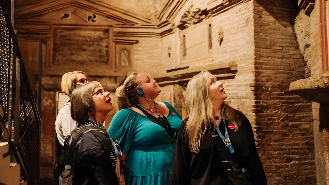 Tour group with audio guides exploring underground catacombs in Rome.