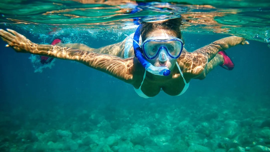 Snorkeler exploring underwater near Isole Ciclopi, Catania.