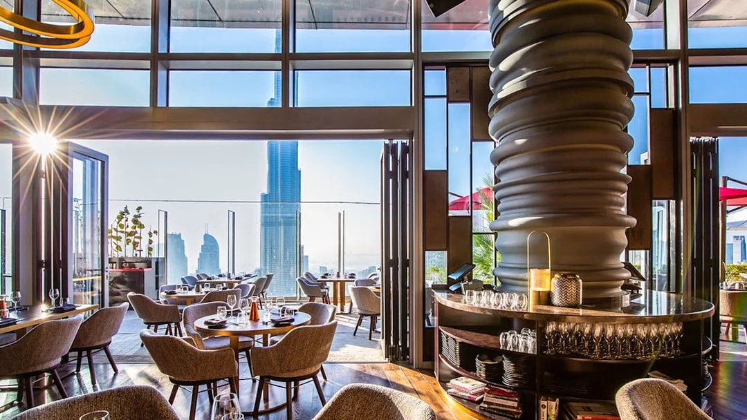 Dining area at CÉ LA VI Dubai with Burj Khalifa view through large windows.
