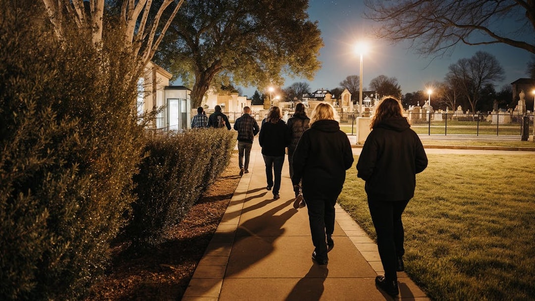 Tour group walking through a cemetery at night on a haunted bus tour.