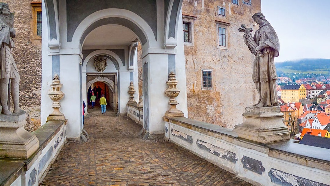 Cesky Krumlov Castle bridge with statues and archway, Czech Republic.