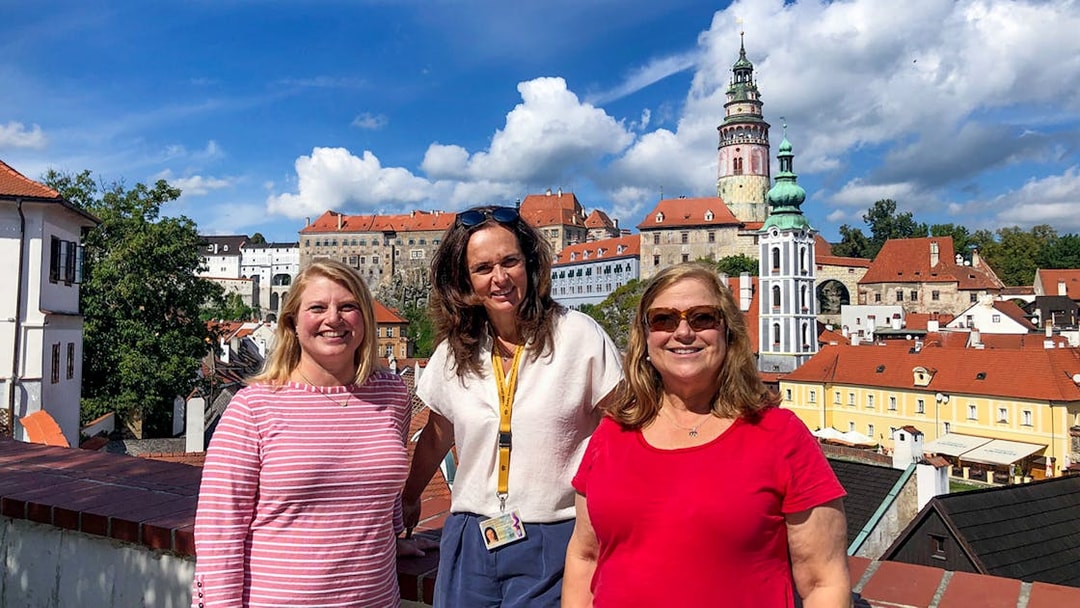 Tour guide with tourists in Cesky Krumlov, castle and town view in background.