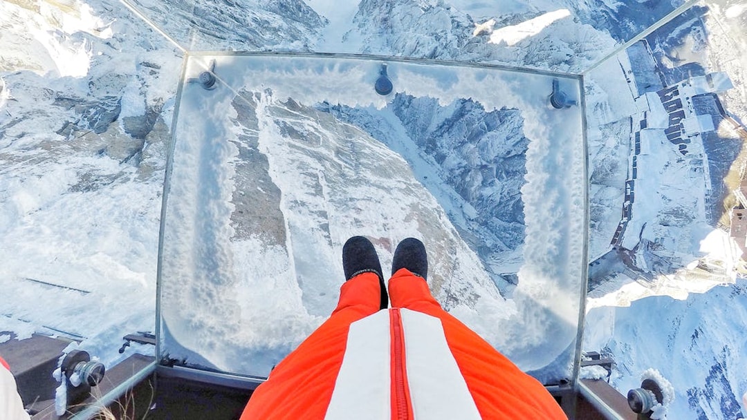 View from a glass platform overlooking snowy Chamonix Mont Blanc during a cable car ride.