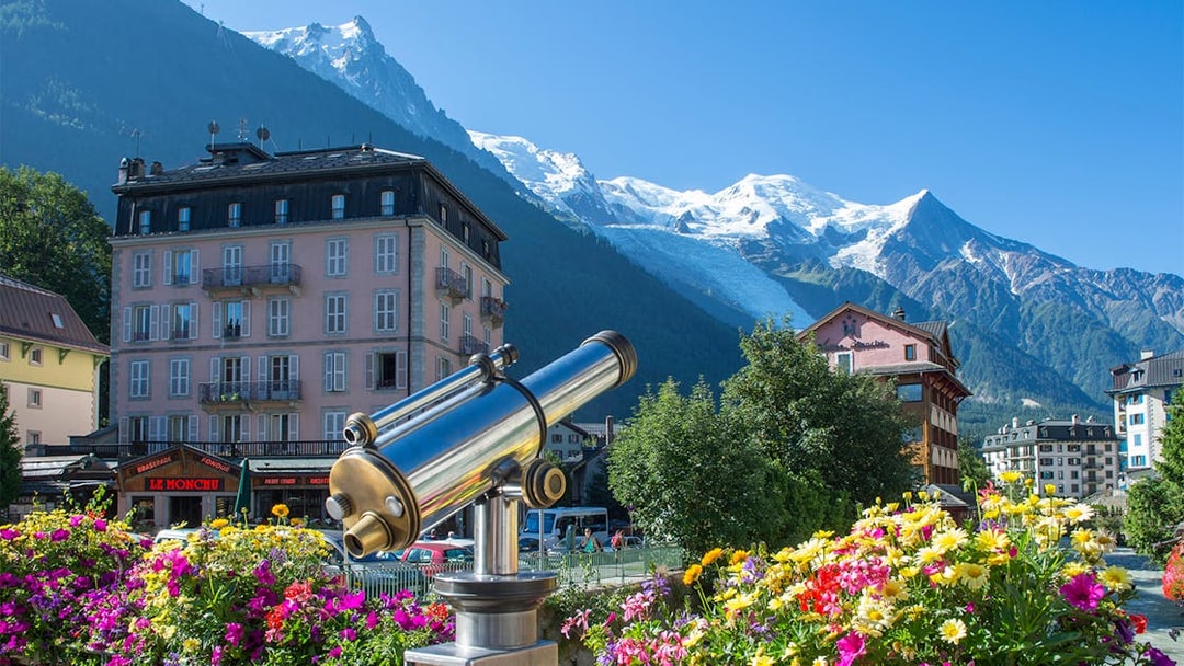 Telescope view of Chamonix Mont Blanc with colorful flowers and mountain backdrop.