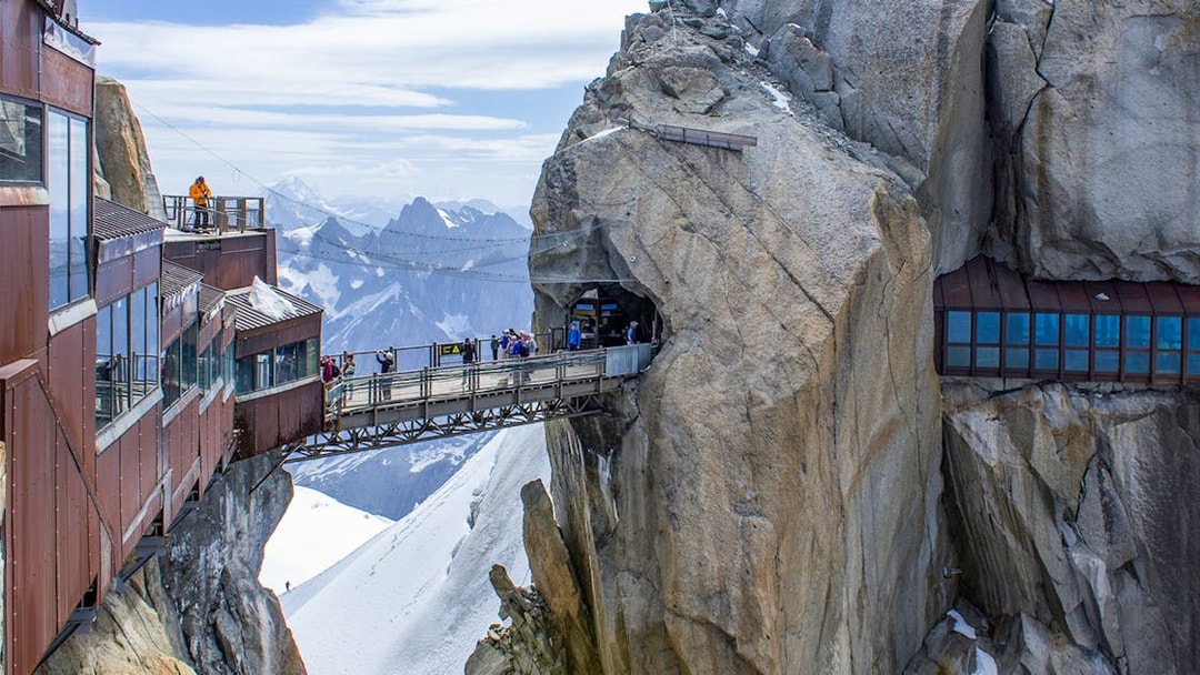 Tourists on a bridge at Aiguille du Midi, Chamonix, with Mont Blanc in the background.