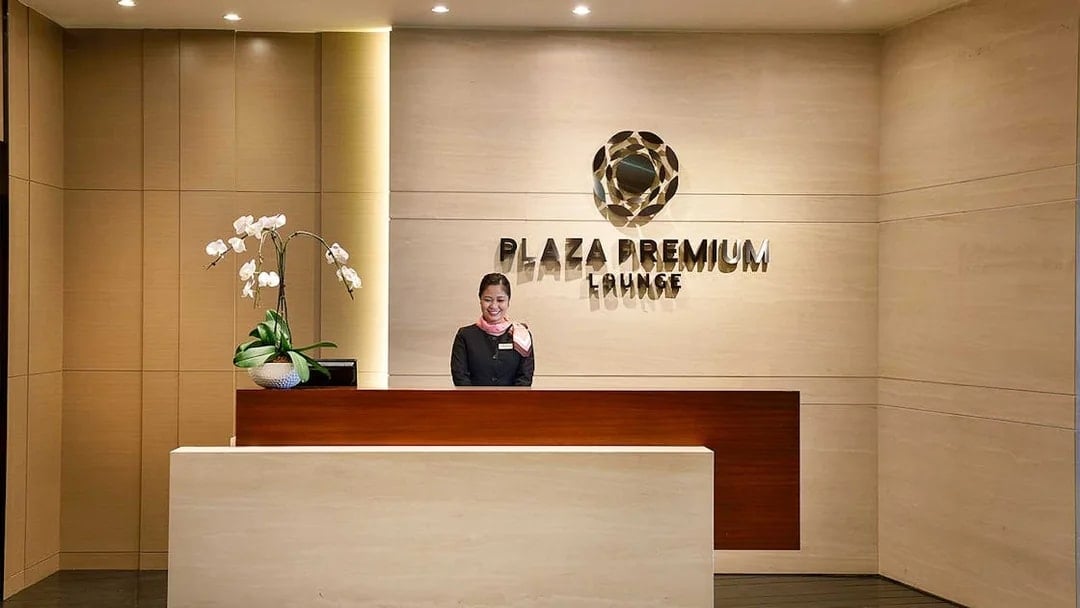 Plaza Premium Lounge reception desk at T1 International Departures with staff member.