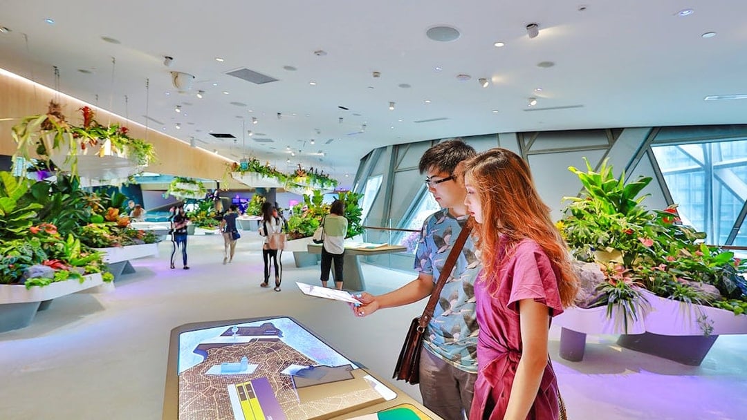 Visitors engaging with interactive displays at Changi Experience Studio, surrounded by hanging gardens.