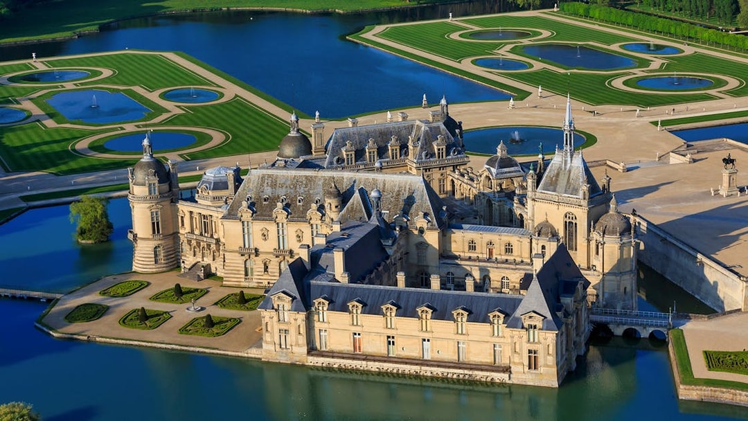 Chateau of Chantilly surrounded by gardens and water features in France.