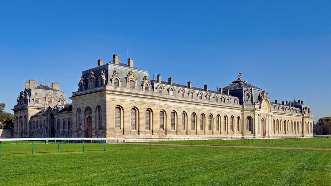 Chateau of Chantilly with expansive lawn and historic architecture in France.