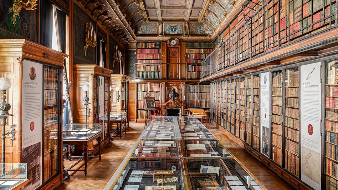 Chateau of Chantilly library interior with ornate ceiling and book displays.