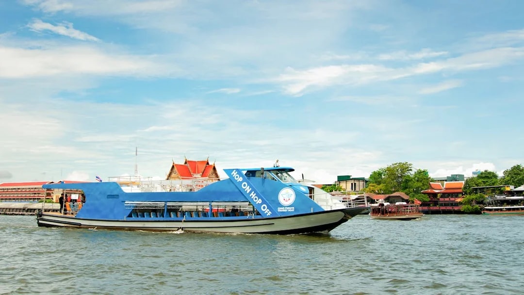 Chao Phraya tourist boat on Bangkok river with temples in the background.