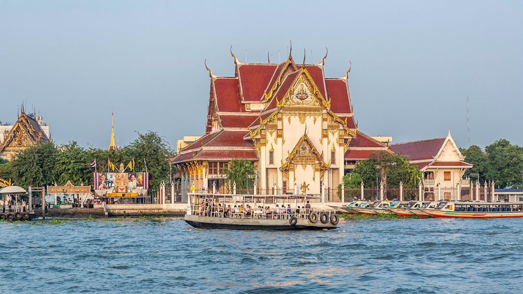 Boat on Chao Phraya River passing Wat Kalayanamit temple in Bangkok.