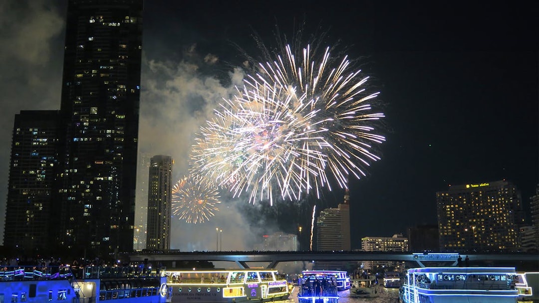 Fireworks over Chao Phraya River with cruise boats in Bangkok.