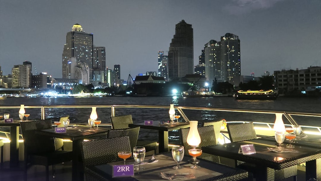 Dining setup on Chao Phraya Princess Cruise with Bangkok skyline at night.
