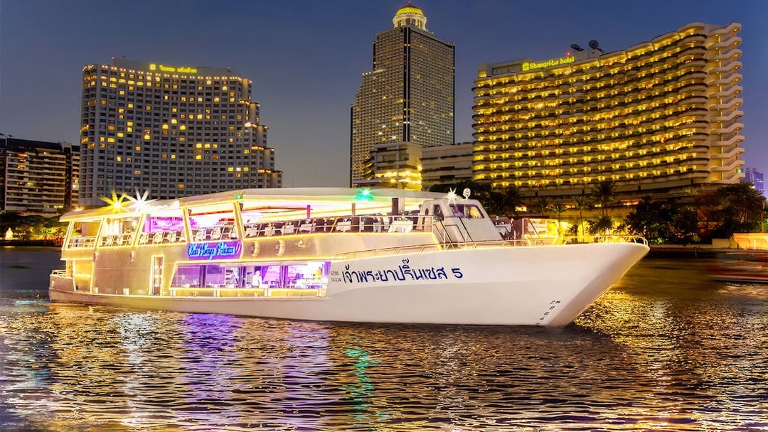 Chao Phraya Princess Cruise on river with Bangkok skyline at night.