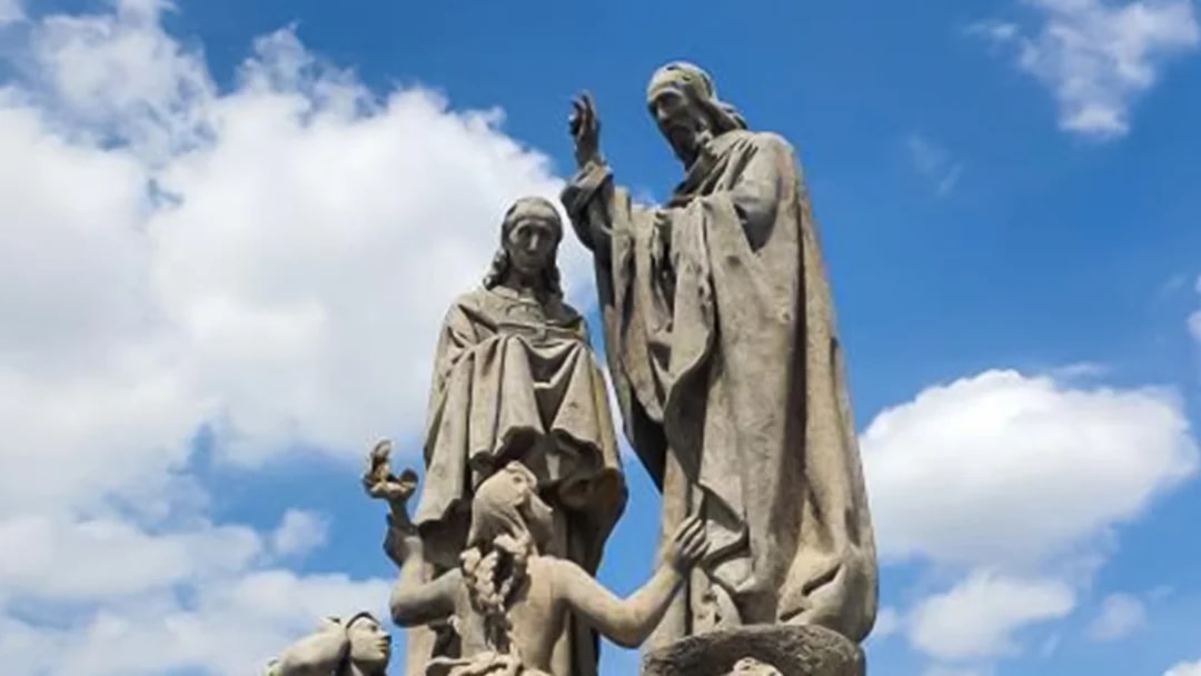Statues on Charles Bridge in Prague under a blue sky.