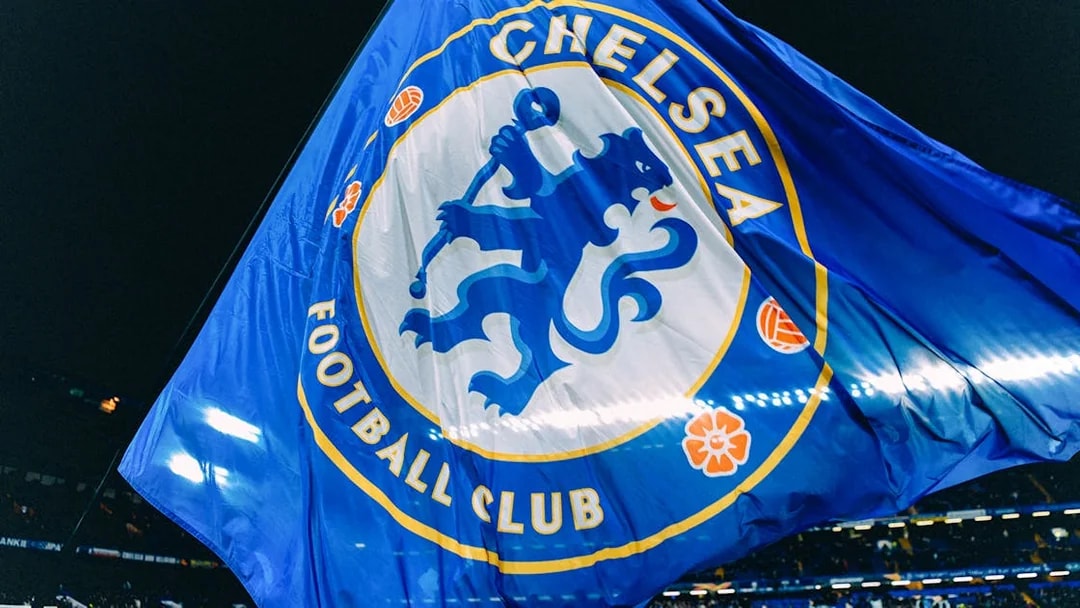 Chelsea FC flag waving at Stamford Bridge stadium during a night event.