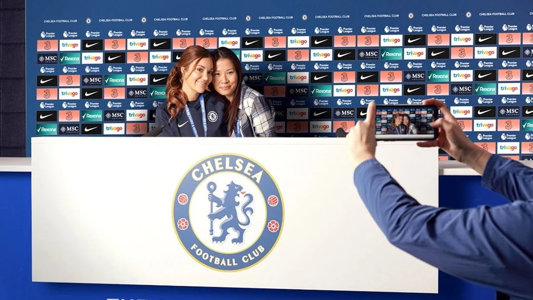 Chelsea FC press room with visitors posing for a photo during stadium tour.