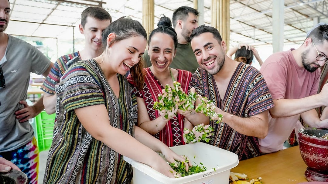 Visitors preparing elephant meal at a sanctuary, mixing greens in a bowl.