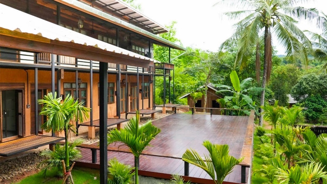 Lodge with wooden deck surrounded by lush greenery at Elephant Jungle Sanctuary, Chiang Mai.