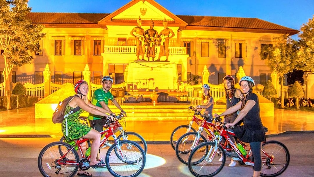 Cyclists in front of the Three Kings Monument during Chiang Mai night bike tour.