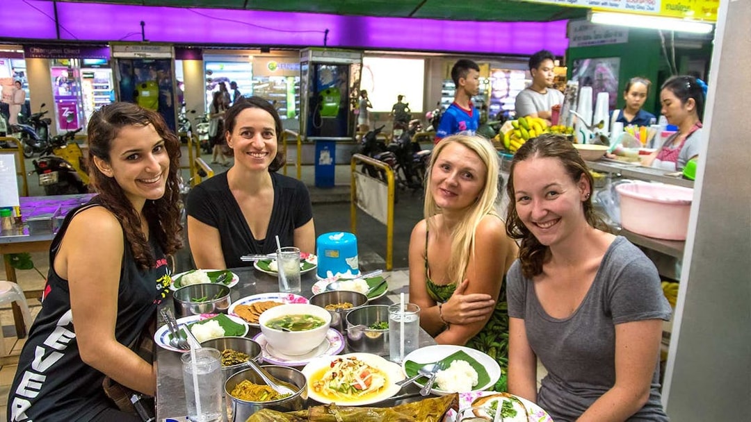 Group enjoying local food at a Chiang Mai night market during a bike tour.