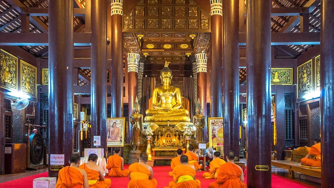 Monks meditating in front of a golden Buddha statue in a Chiang Mai temple.