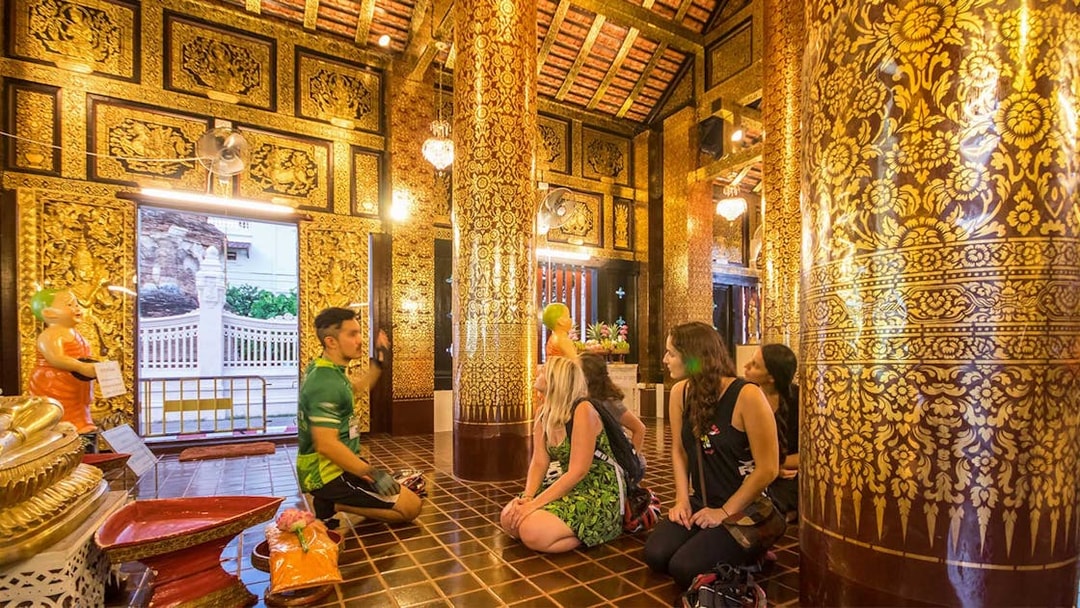 Participants listening to a guide inside a decorated temple during Chiang Mai Night Bike Tour.