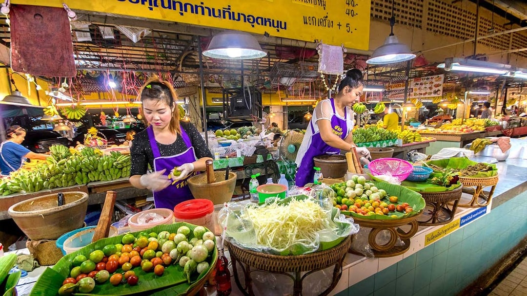 Chiang Mai market vendors preparing fresh produce during night bike tour.