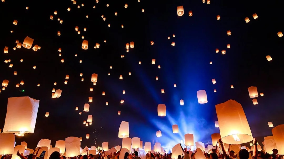 People releasing lanterns into the night sky at Chiang Mai Sky Lanterns Festival 2025.