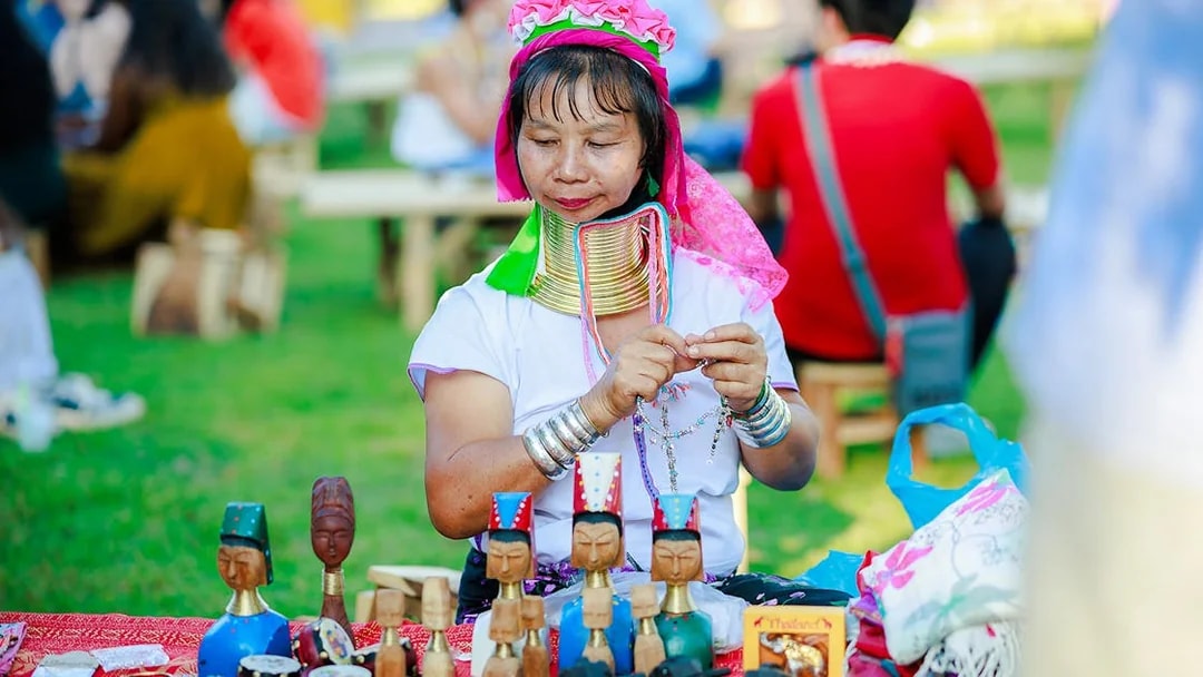 Woman crafting jewelry at Chiang Mai market during Sky Lanterns Festival.