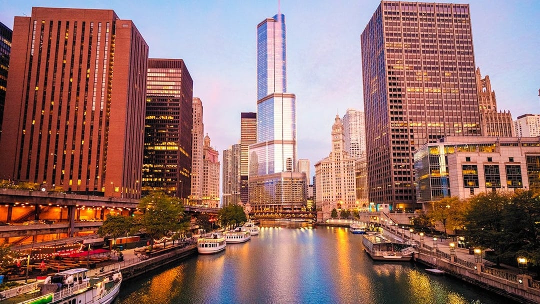 Moored tour boats on the Chicago River at sunrise with city skyline.