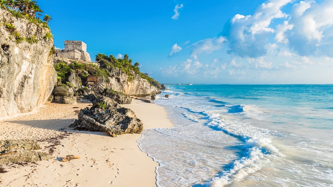 White sand beach with Tulum ruins on cliffs, Yucatan, Mexico.