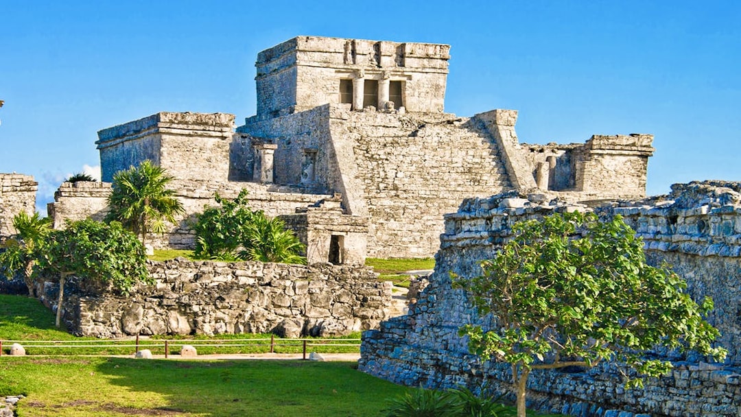 Ancient stone structures of the Mayan city of Tulum, Mexico, with clear blue sky.