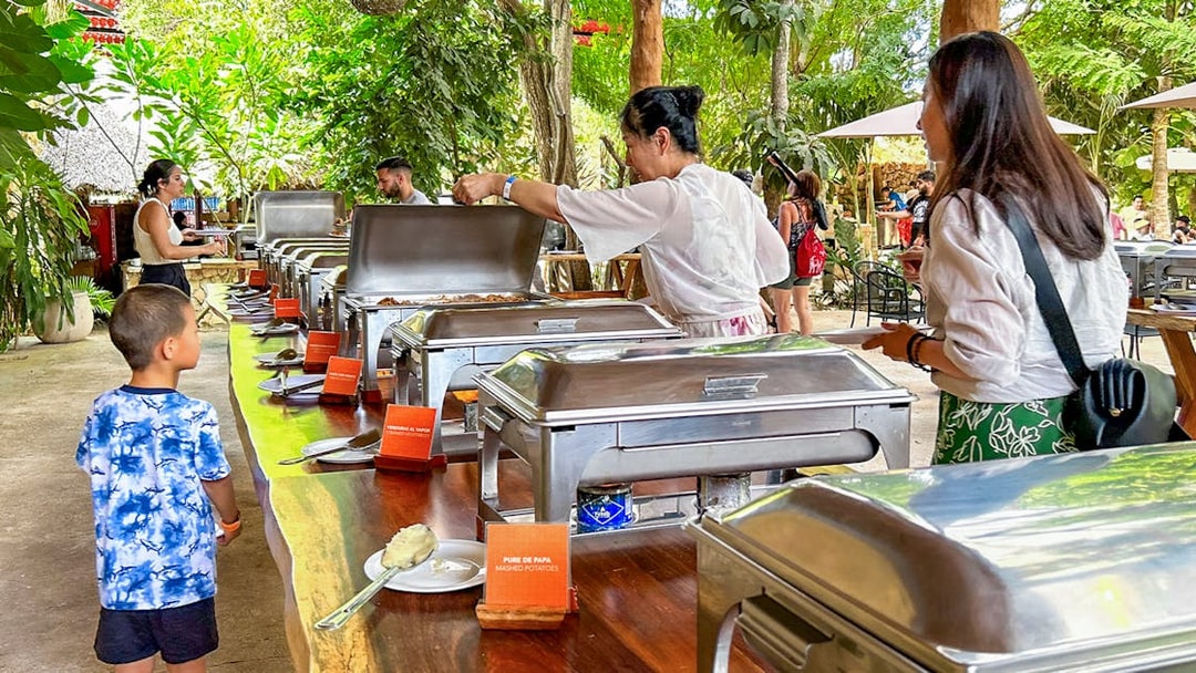 Tourists enjoying buffet during Chichen Itza sunrise tour in lush outdoor setting.