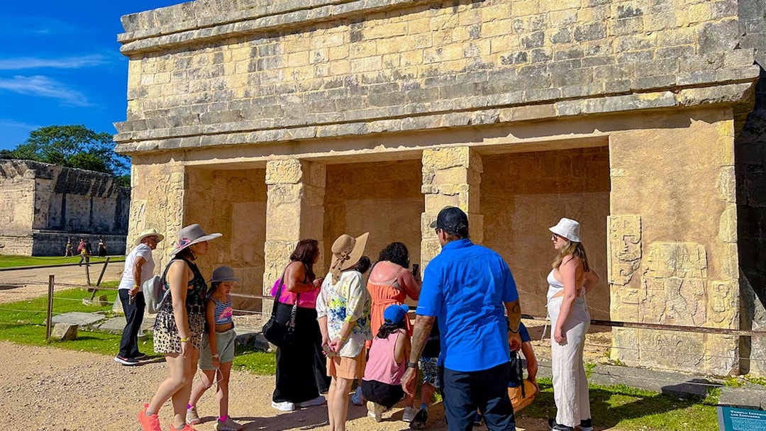 Tourists exploring ancient structures at Chichen Itza during sunrise.