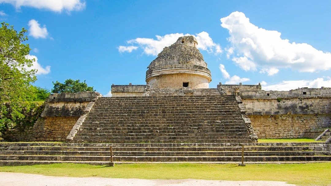 Chichen Itza observatory with stone steps under a blue sky.