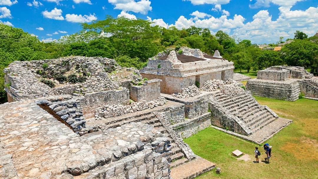 Ek Balam ruins with stone structures and tourists, Yucatan Peninsula, Mexico.